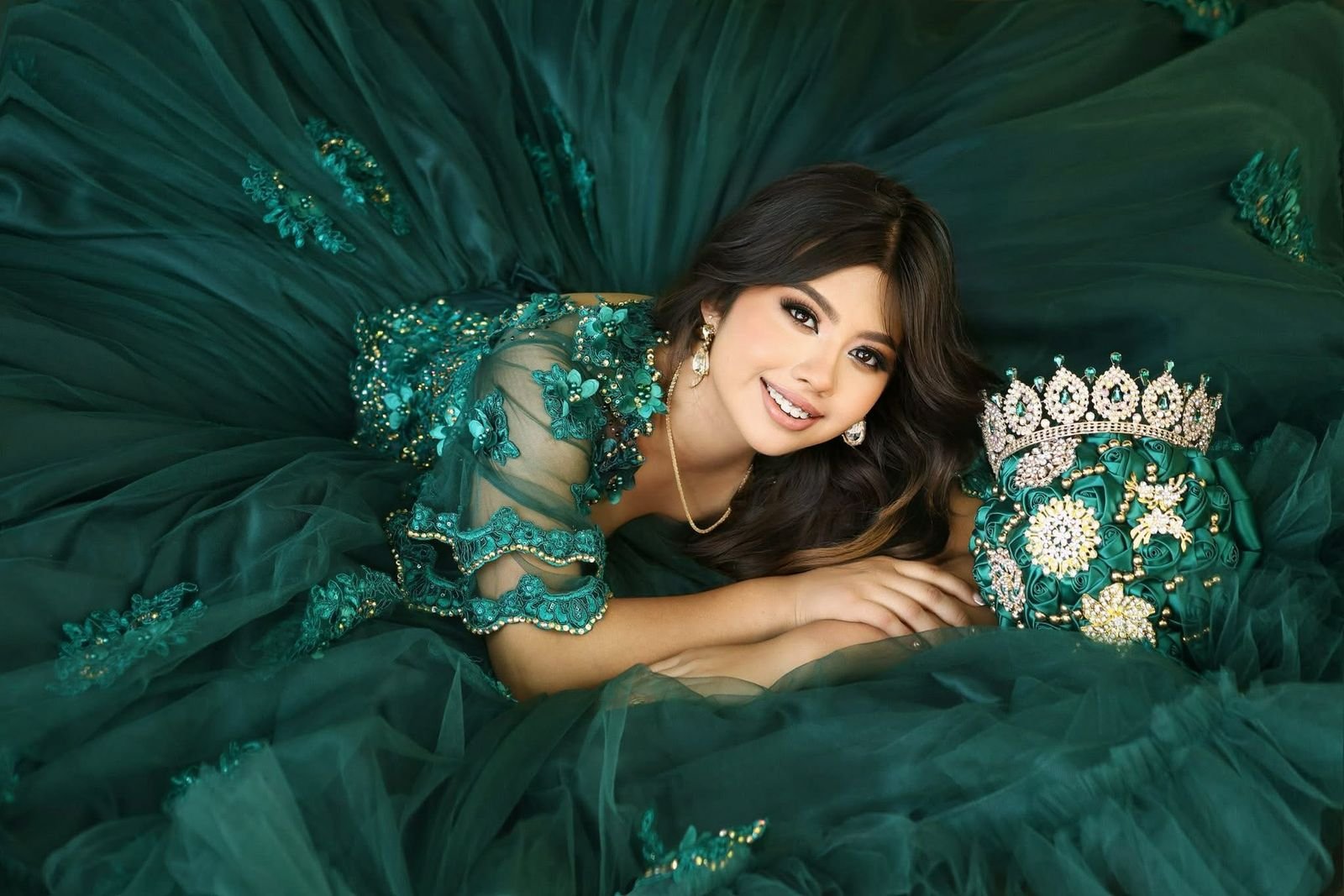 Quinceañera wearing a teal gown with matching bouquet
